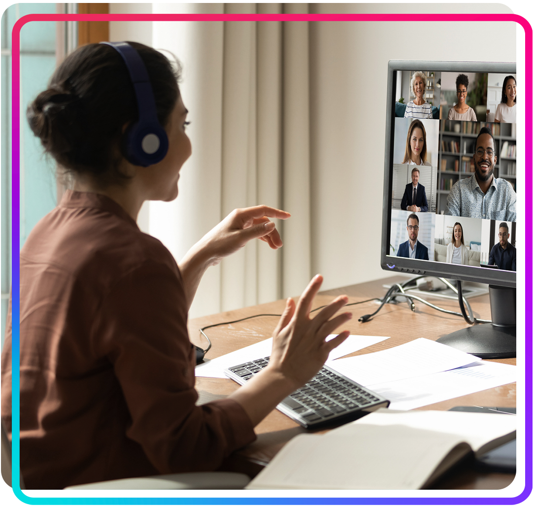 Smiling Indian woman sitting at desk at home office conducting an accessibility training session on video with multiethnic diverse colleagues.
